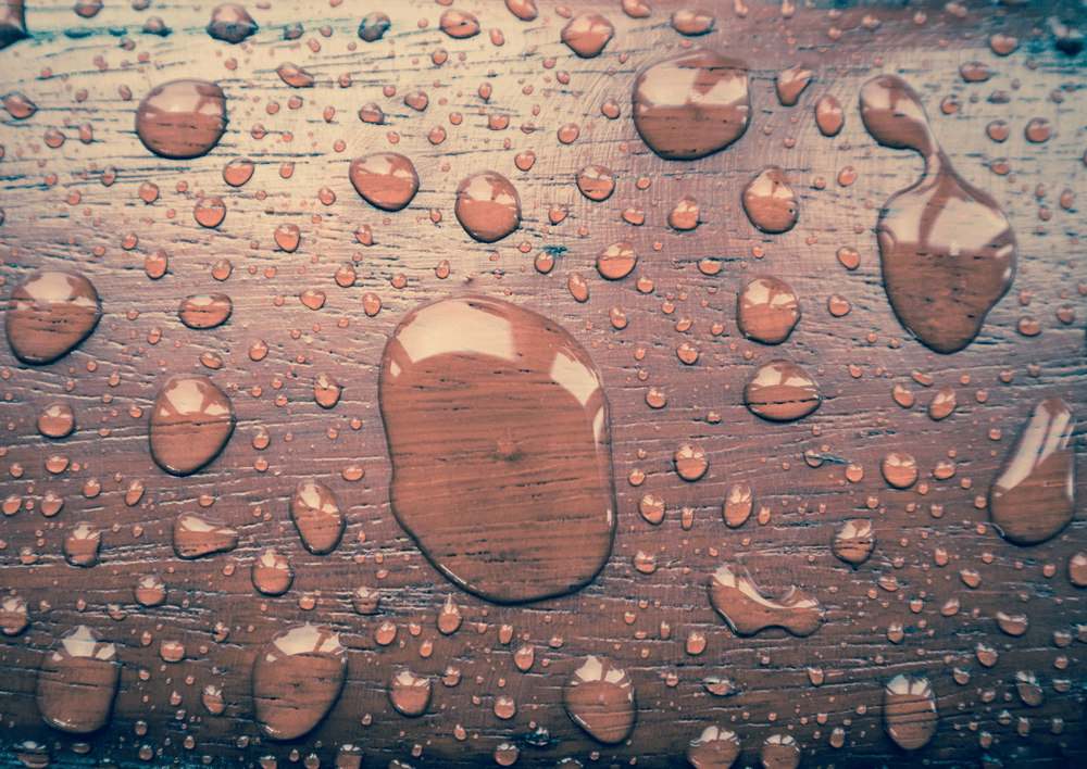 A close up of water drops on a wooden surface.