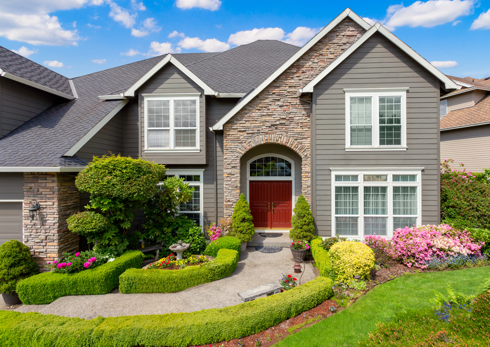 A large house with a red door and a lush green yard.