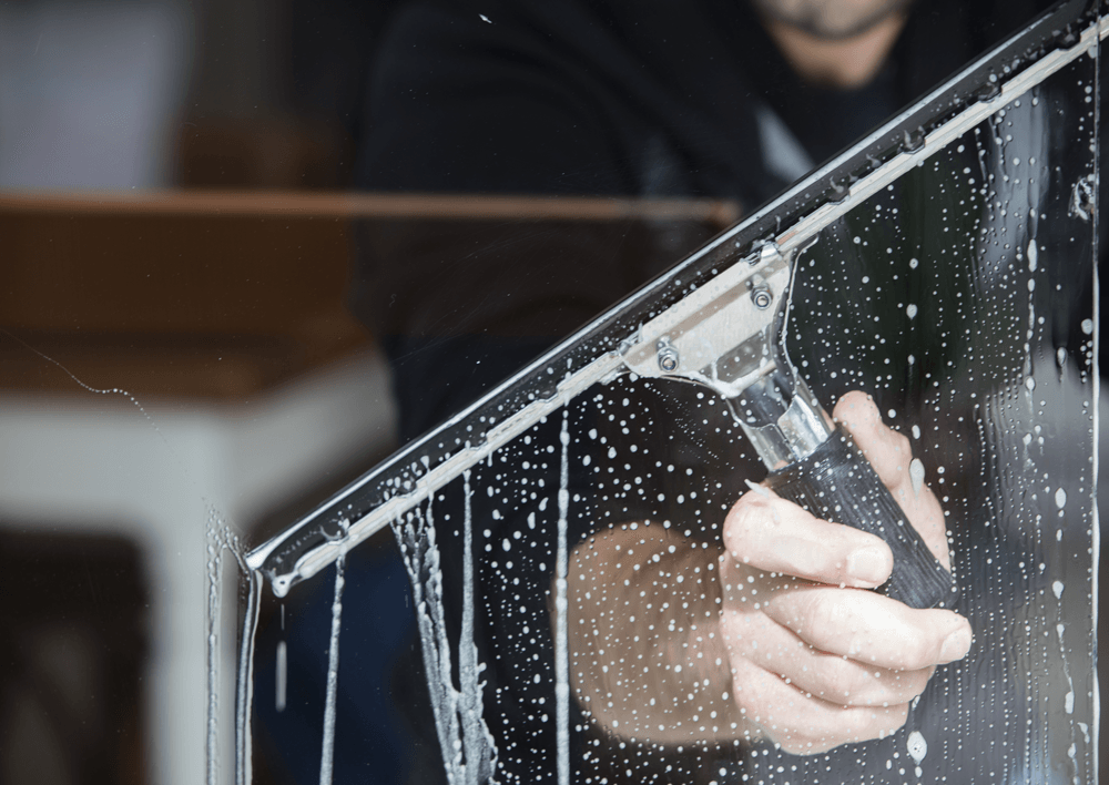 A man is cleaning a window with a squeegee.