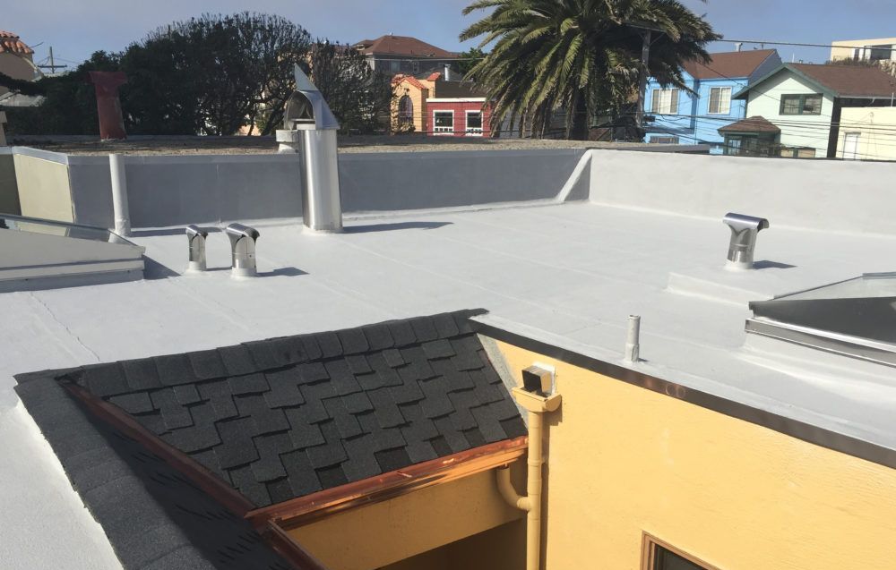 Flat white roof with vent pipes, chimney, skylight, and asphalt shingle roof section.