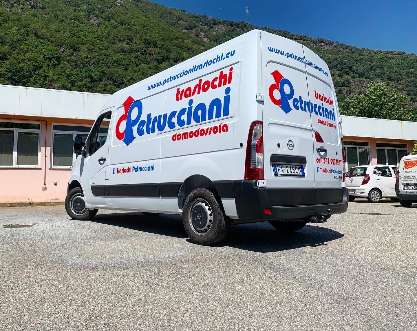 Un furgone bianco della marca Petrucciani parcheggiato in un piazzale ghiaioso con una collina sullo sfondo, in una giornata di sole.