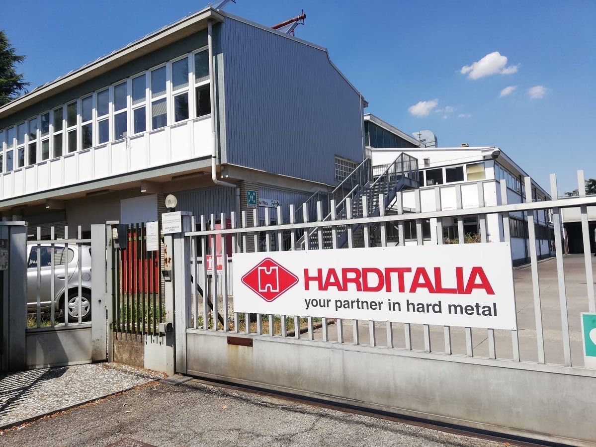 Un impianto di Harditalia con un'insegna bianca che mostra il logo rosso dell'azienda dietro un cancello metallico grigio.