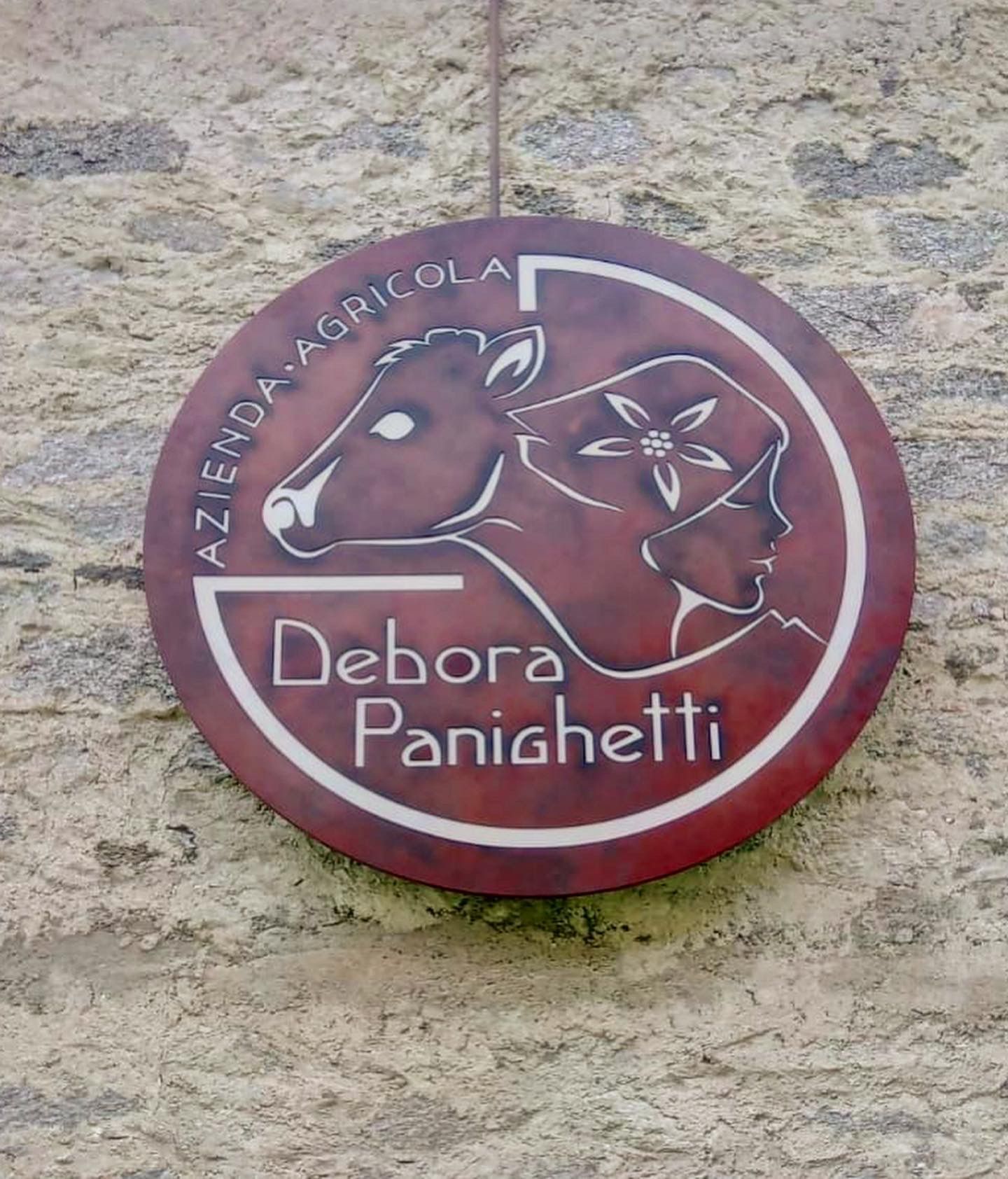 Un cartello circolare su un muro di pietra con la scritta 