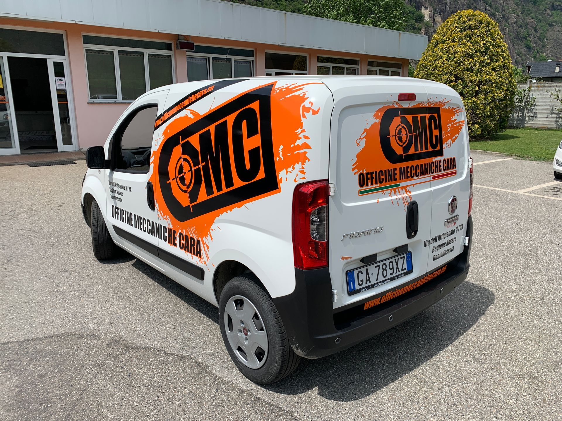 Furgone bianco per il trasporto merci parcheggiato all'aperto, con il marchio OMC ben visibile in arancione e nero sulle portiere laterali e posteriori.