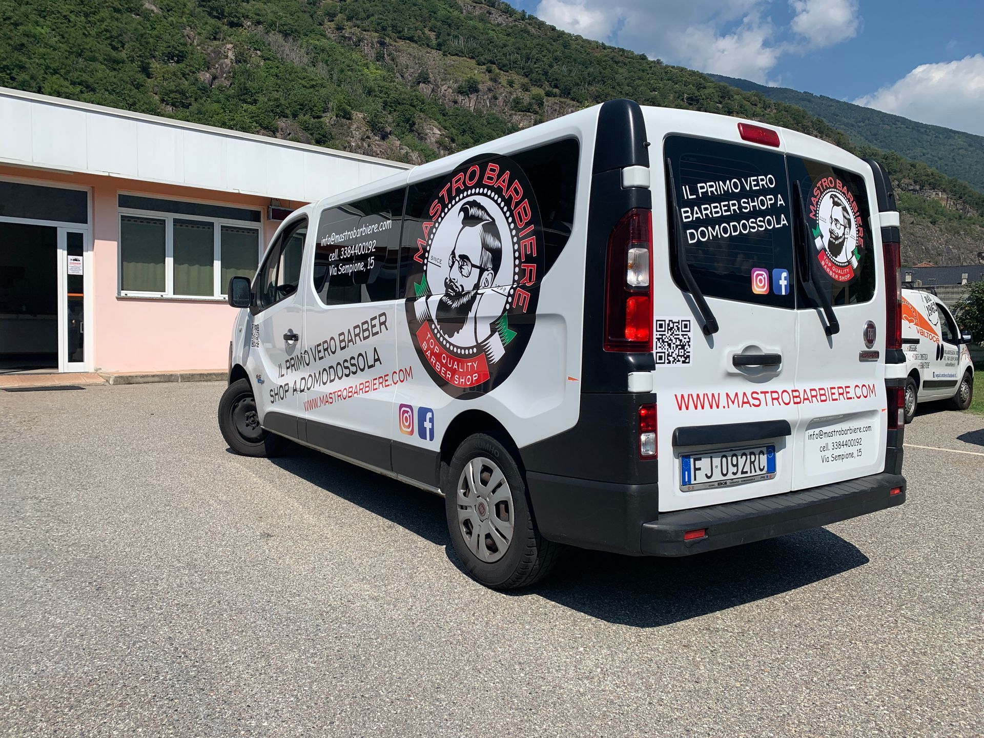 Un furgone bianco di servizio parcheggiato in un piazzale sterrato, con il marchio 