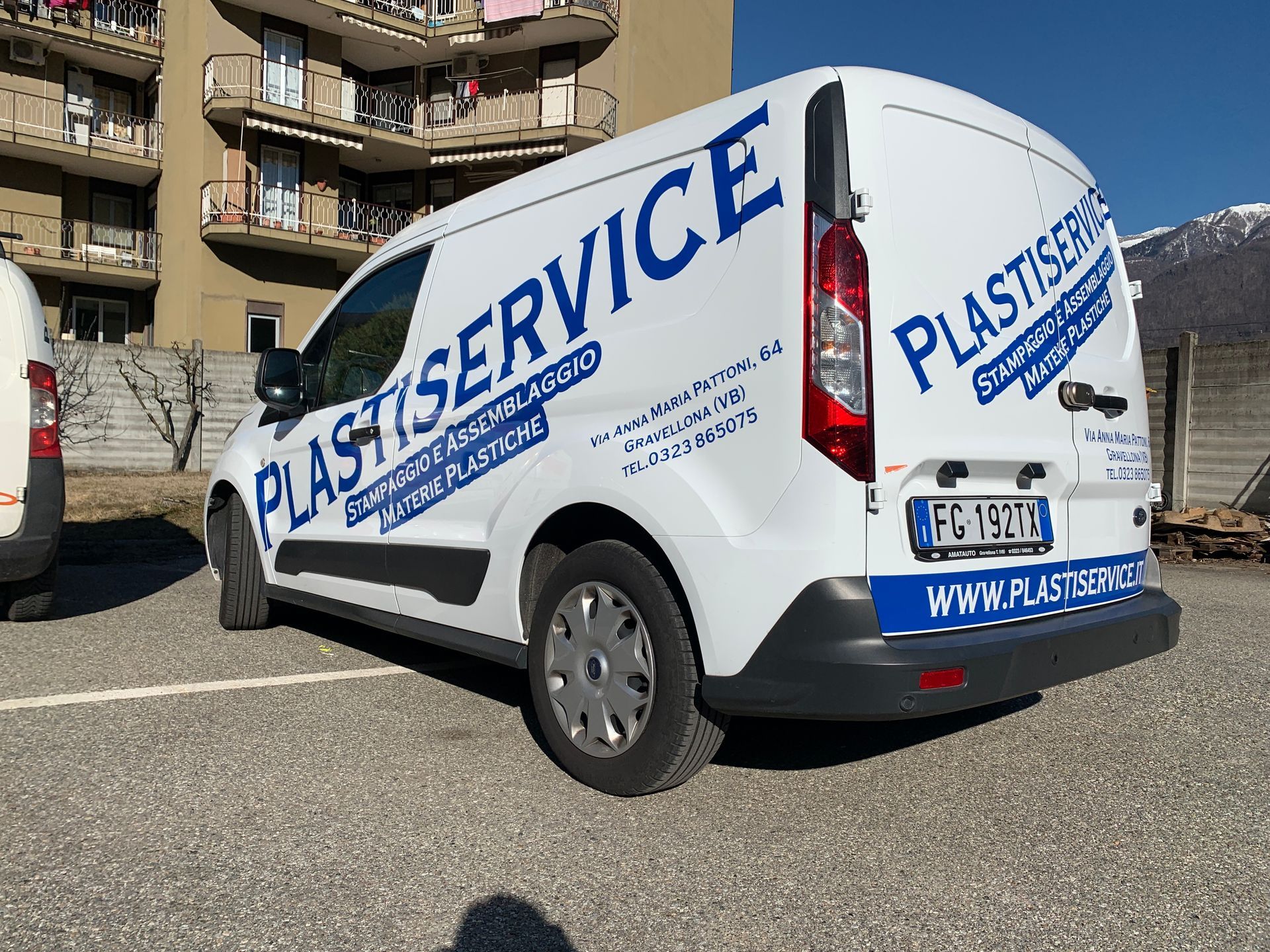 Un furgone bianco parcheggiato all'esterno, con il logo 