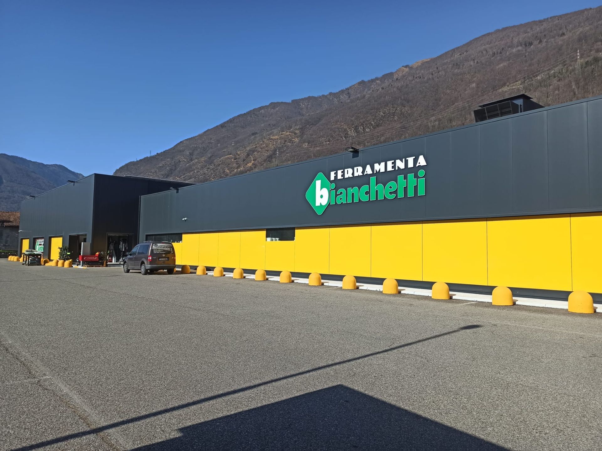 Un edificio di ferramenta grigio e giallo con il logo verde 