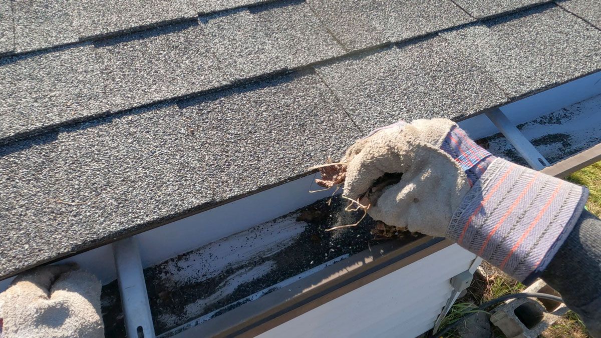 A person is cleaning a gutter on a roof.