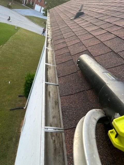 A gutter is being cleaned on the roof of a house