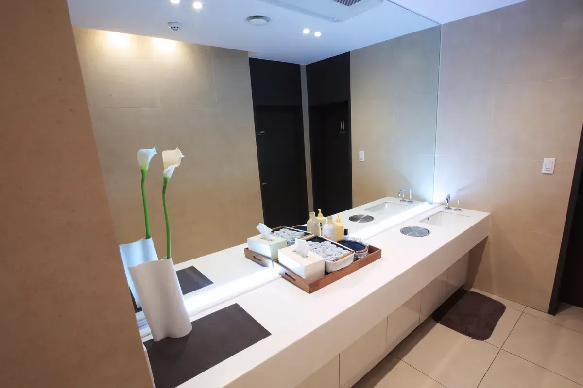 Modern lounge with gray sofas, glass walls, and orange accent chairs in a sleek office interior