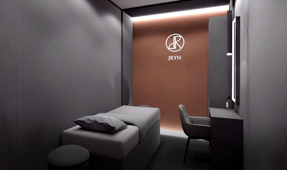 Modern minimalist room with a single bed, desk, chair, and warm backlit wall panel