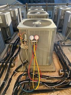 An air conditioner is being serviced by John's Heating, Cooling, and Appliance Repair on top of a roof in Peachtree City, Ga.