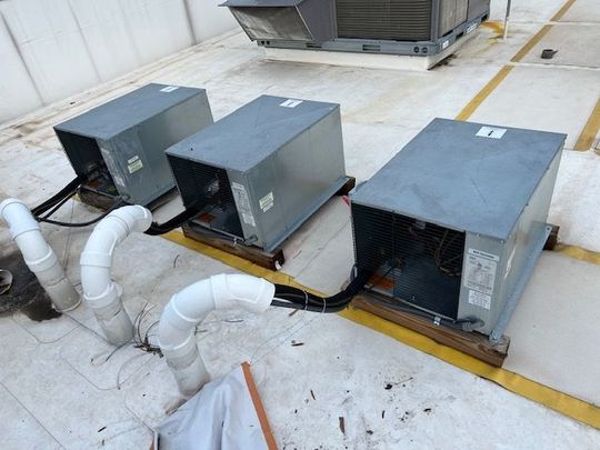 Three air conditioners are on the roof of a building