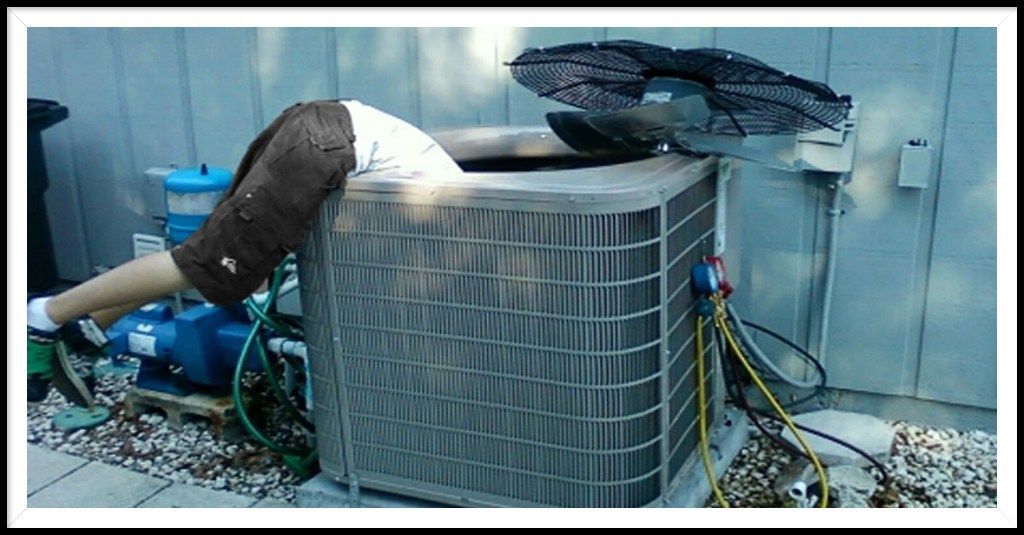 A man is laying on the ground next to an air conditioner.