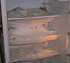 A refrigerator filled with lots of pillows and blankets.