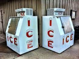 Two ice machines are sitting next to each other in front of a building.