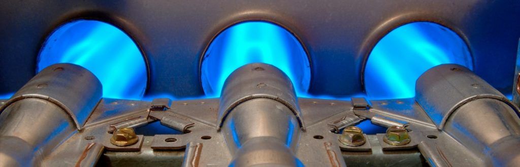 A close up of a gas burner with blue flames coming out of it.