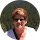 A woman wearing sunglasses is standing in front of a tree.