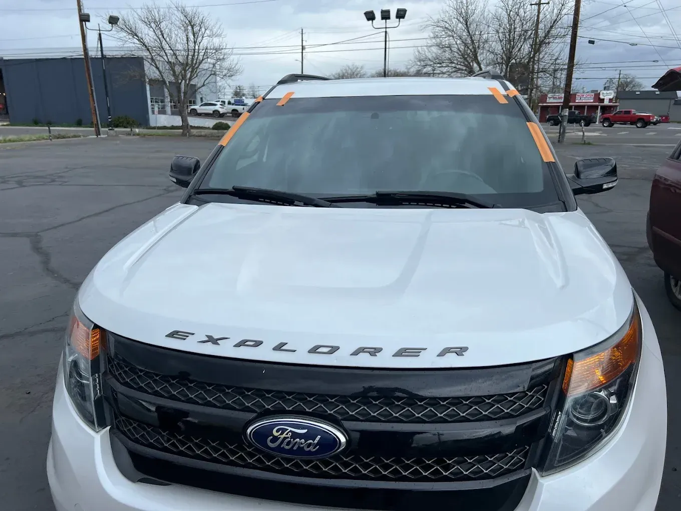White Ford Explorer SUV with black grille and windshield taped. 