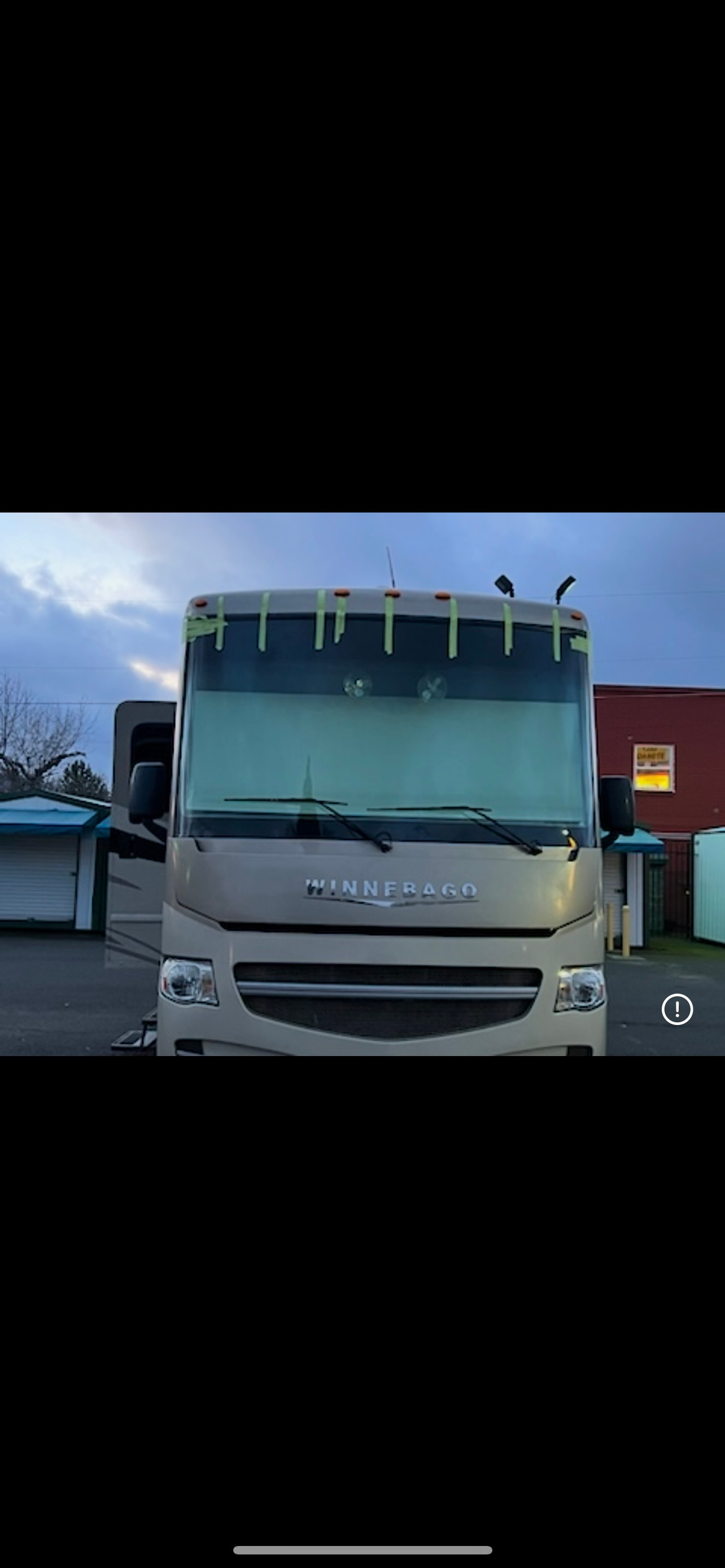 White Isuzu box truck with open doors, parked outdoors.