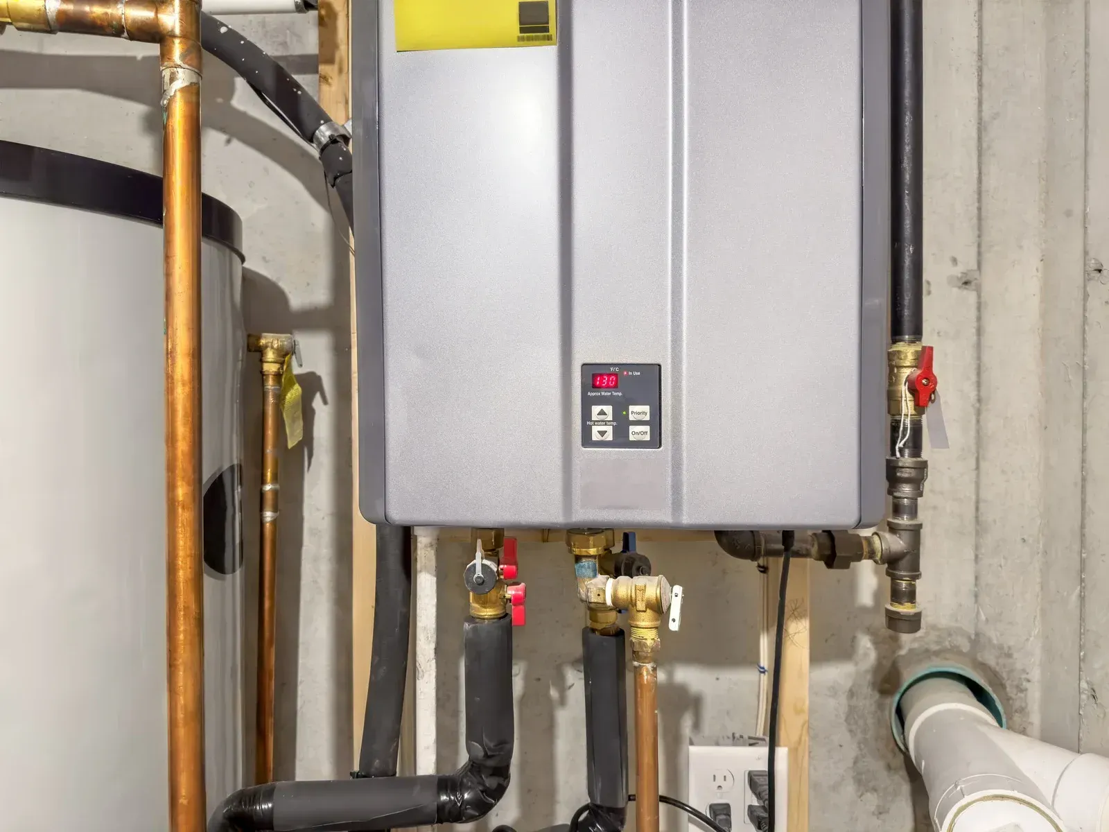Water heater installation with copper pipes, a digital display, and insulation.