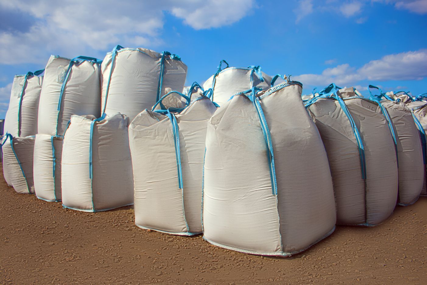 A Bunch Of Bags Stacked On Top Of Each Other On A Dirt Field — Belt Maintenance & Supplies Pty Ltd In Nindaroo, QLD