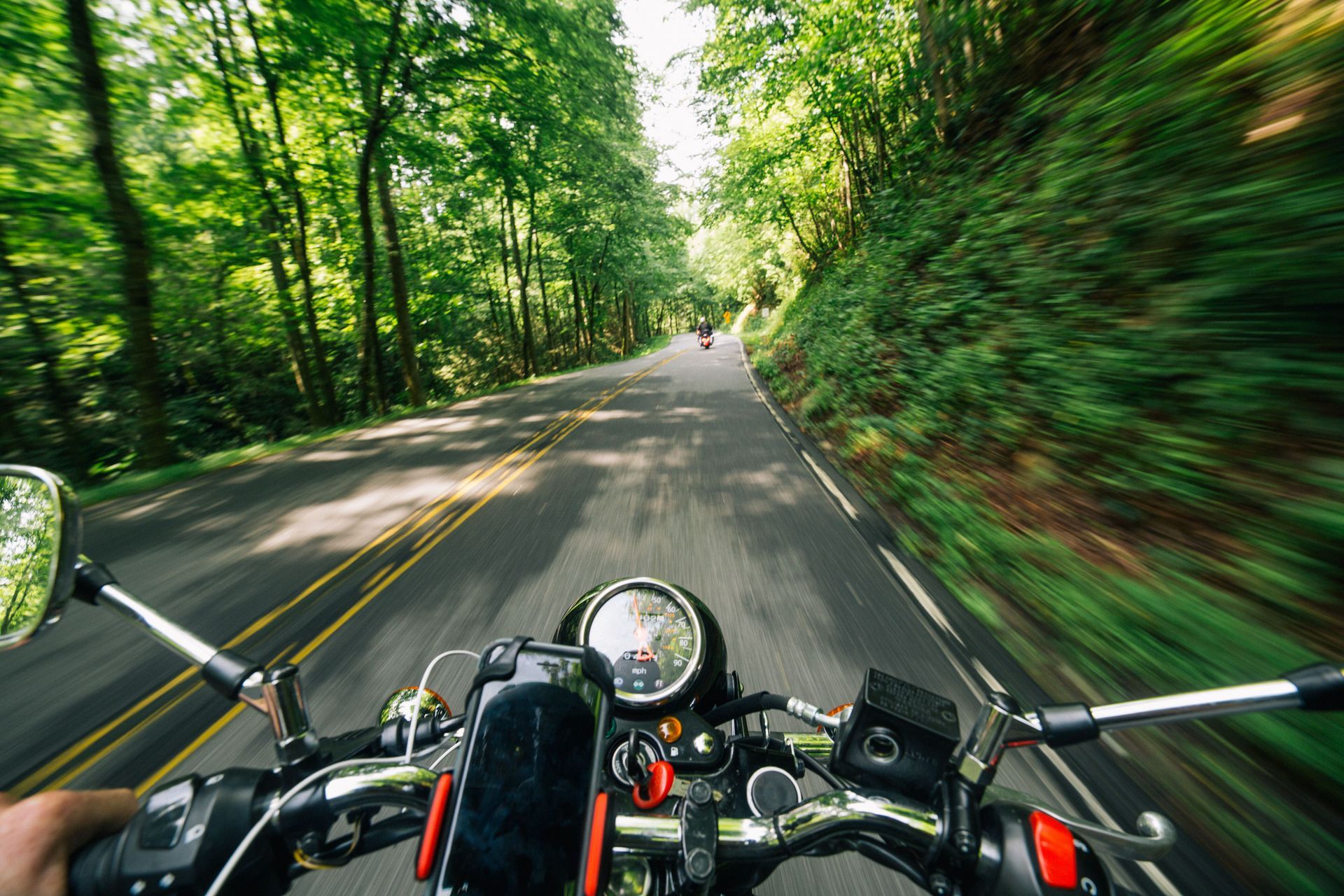 Motorcyclist riding a wooded road near Springfield, Missouri, viewed from another motorcycle.