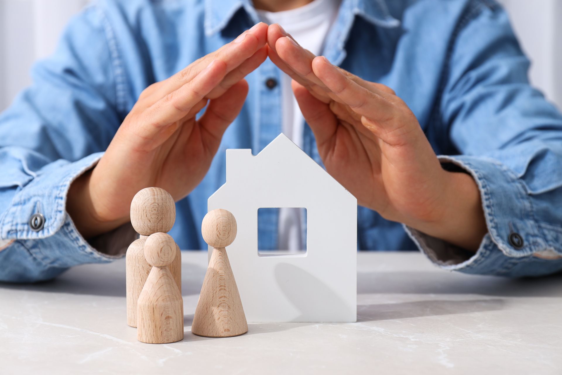 Hands protecting a house model representing homeowners insurance coverage