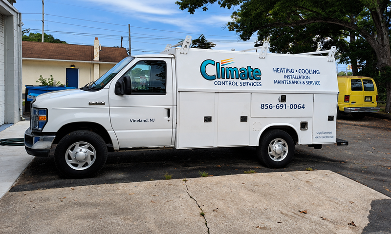 White Climate Control service van parked on a street, with company logo and contact info on the side