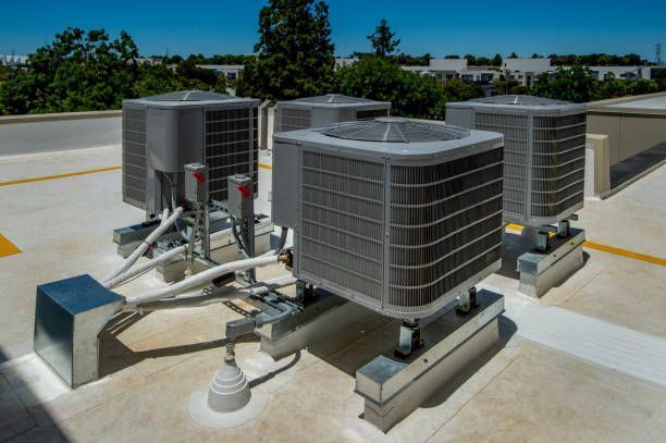 Rooftop HVAC units and ductwork on a commercial building under a clear sky