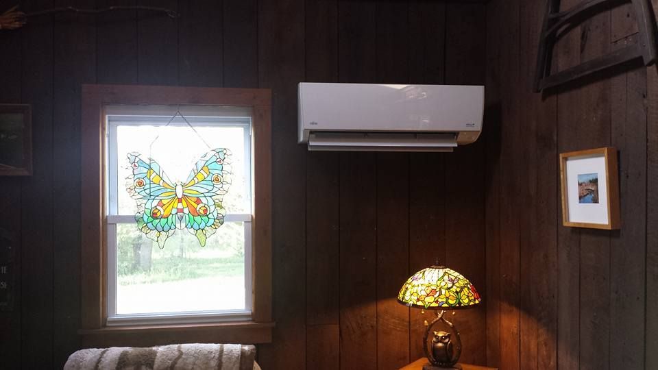 Wood-paneled room with a window, wall AC, stained-glass lamp, and small framed picture