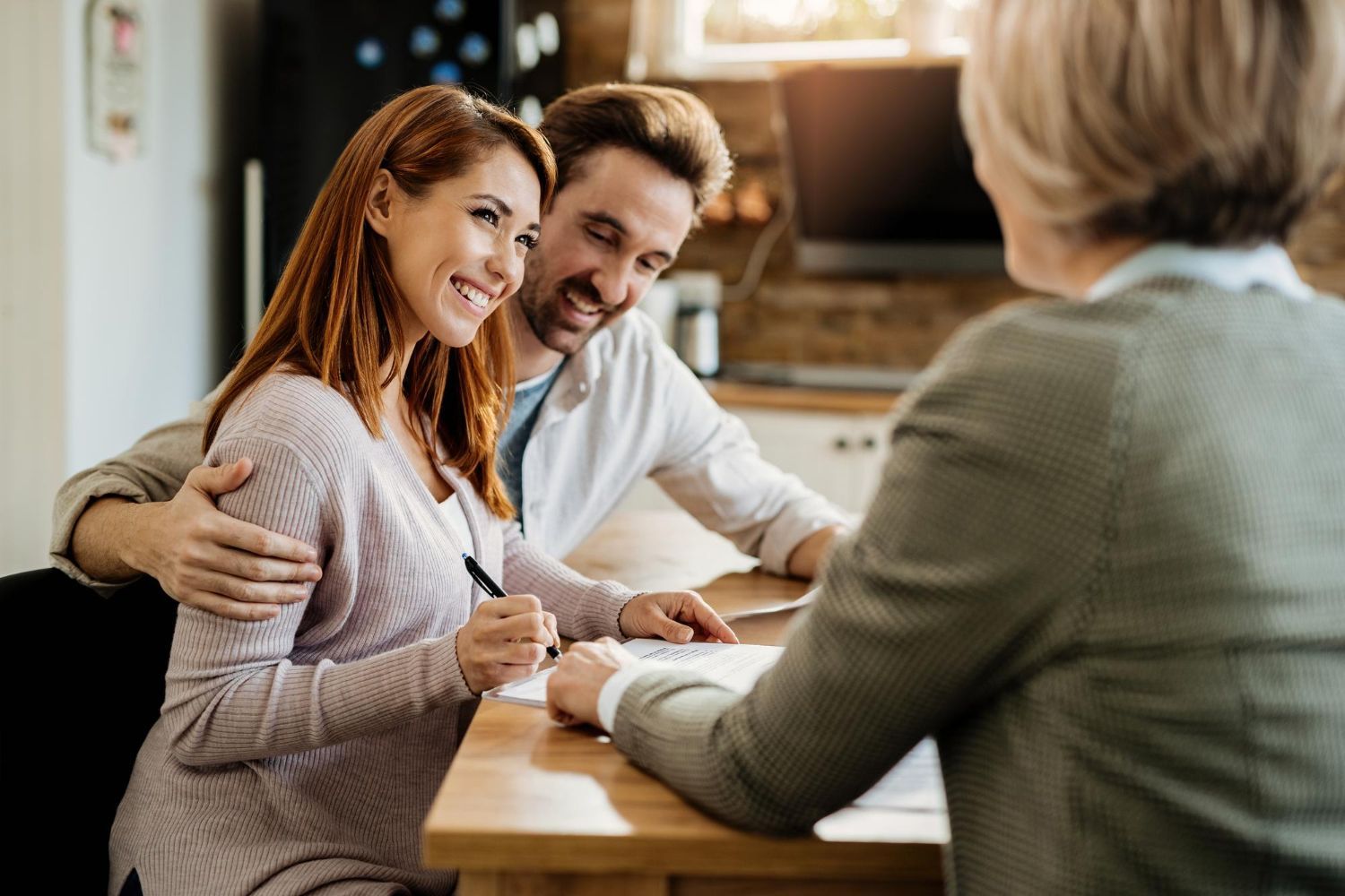 Smiling couple talking with a counselor at a table in a cozy office