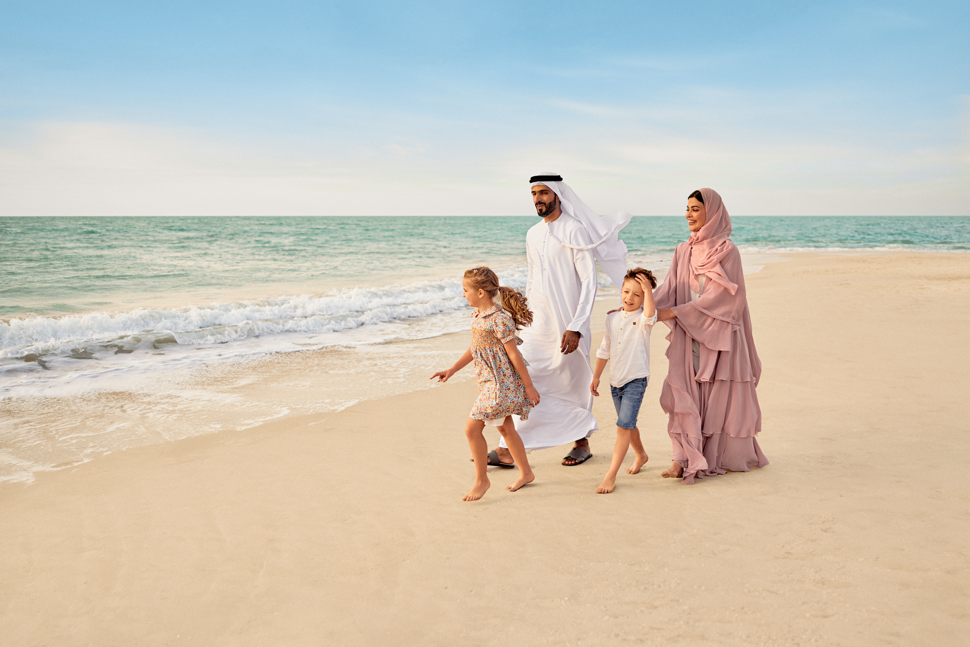 A family enjoying a walk along a sandy beach shoreline