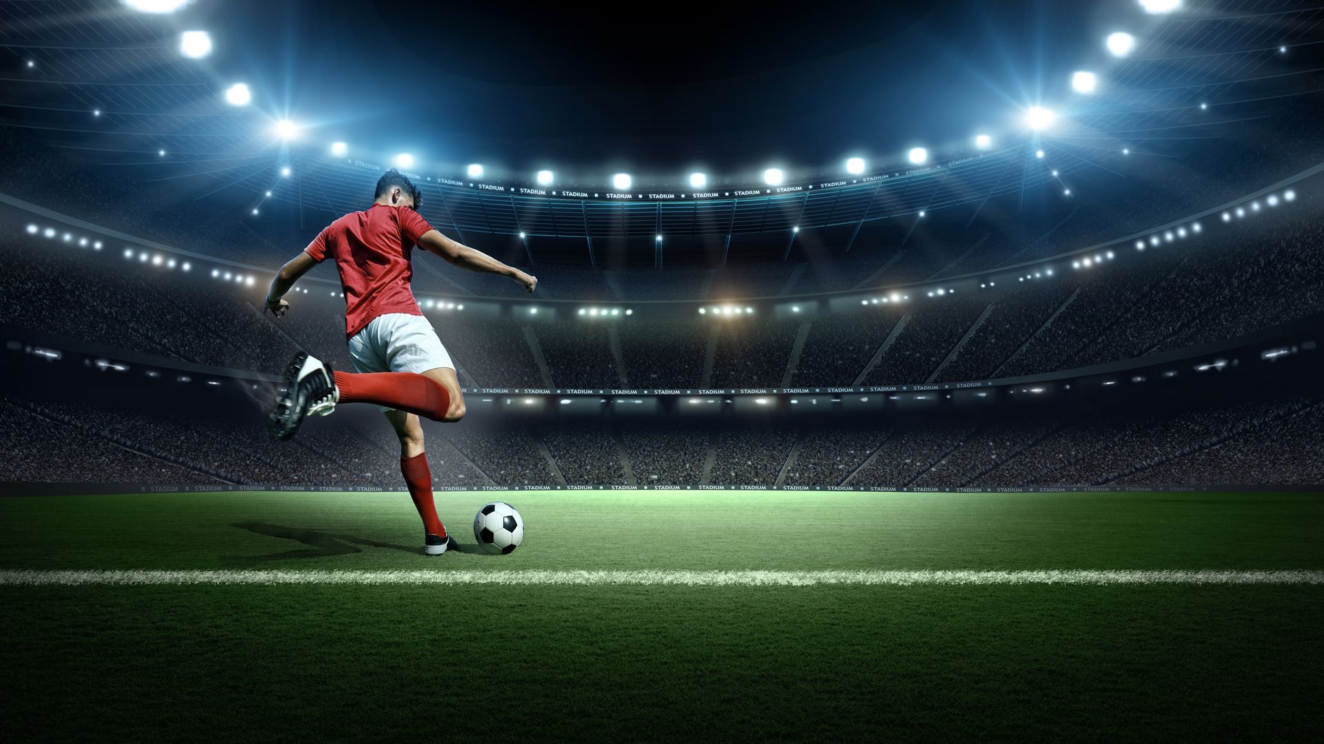 A football player kicking a ball in a brightly lit stadium, representing halal sports holidays