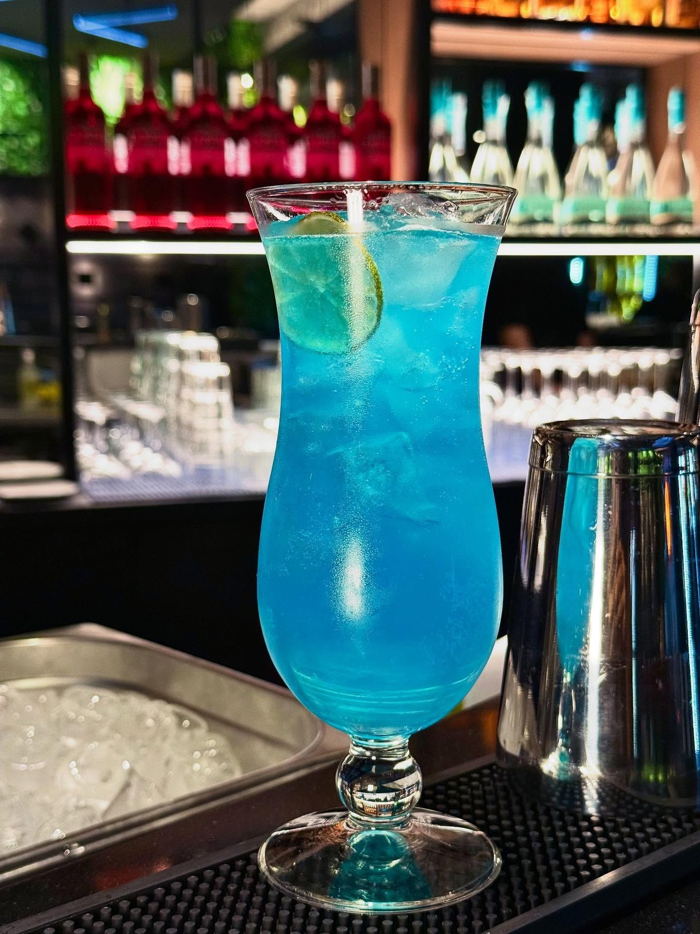 Parete color verde acqua con opere d'arte incorniciate e scritta al neon