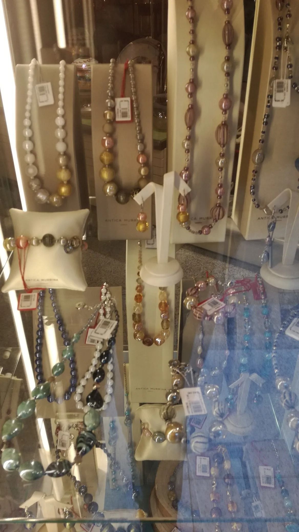 Una varietà di collane e braccialetti sono esposti nella vetrina di un negozio.