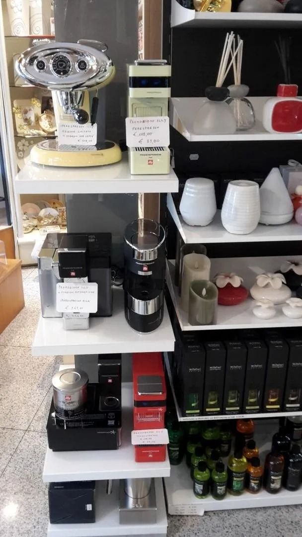 Uno scaffale di un negozio pieno di articoli vari, tra cui macchine per il caffè.