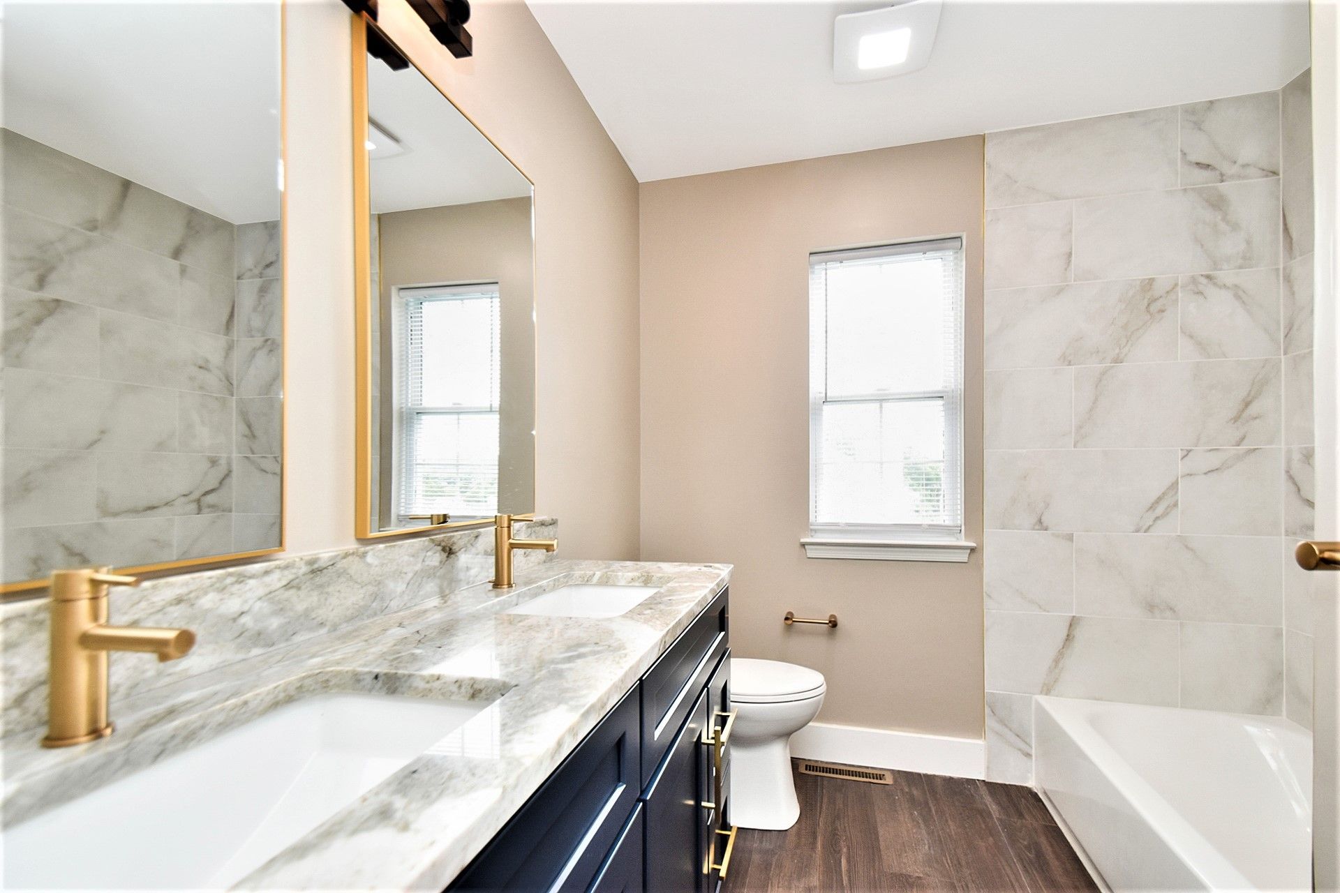 A bathroom with two sinks , a toilet , and a bathtub.