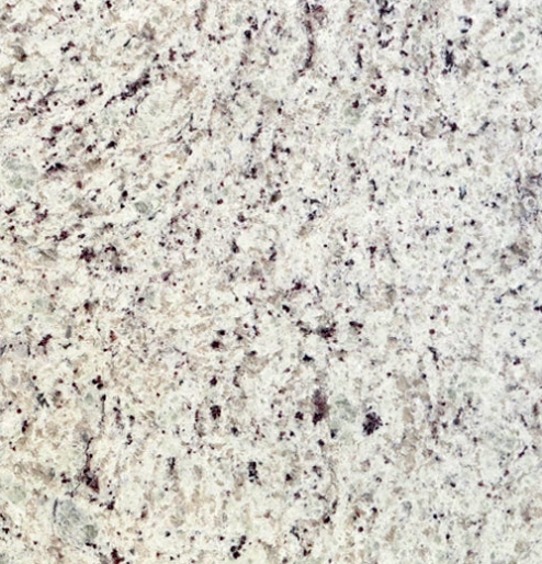 A close up of a white granite counter top with black spots.