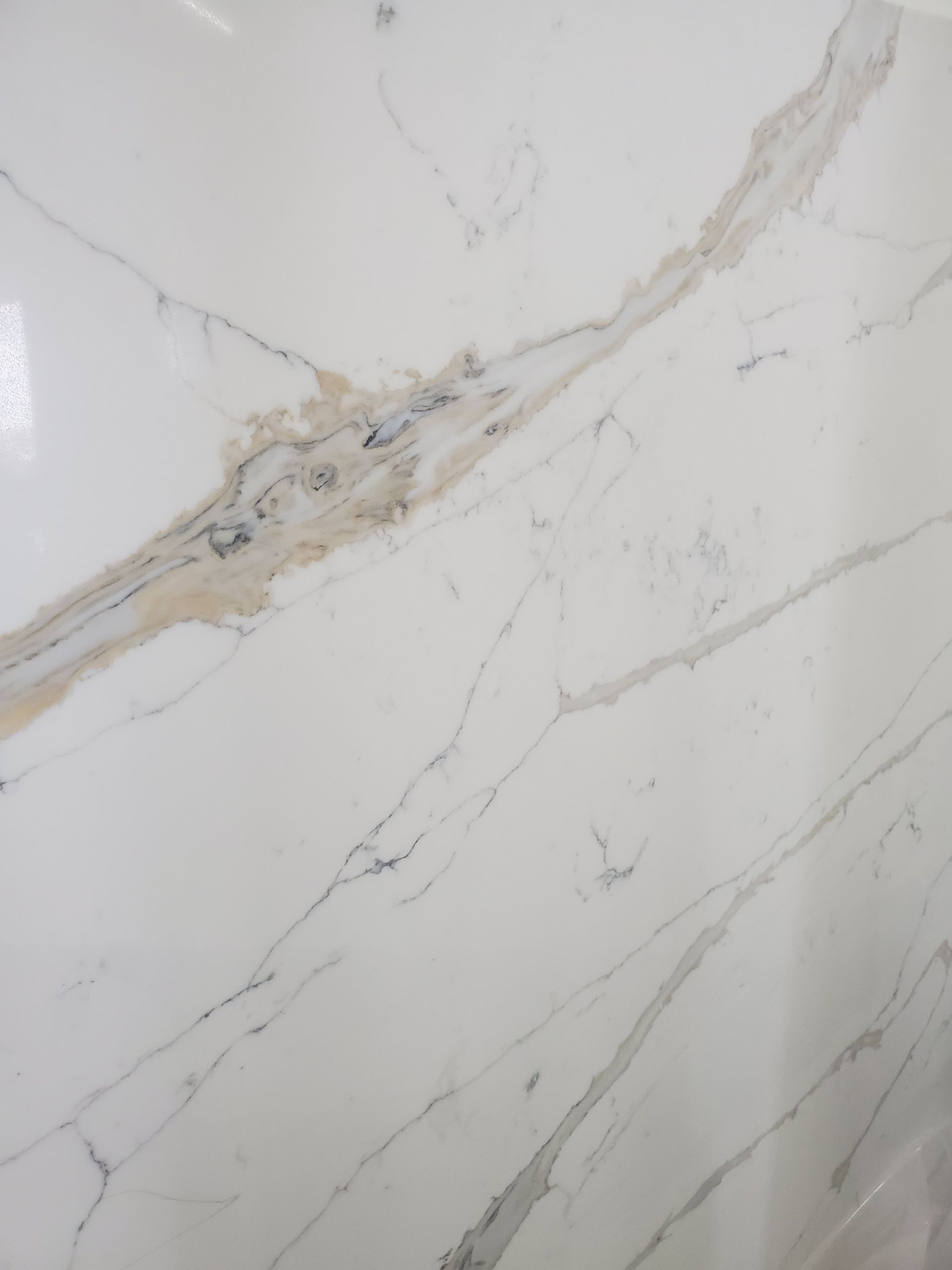 A close up of a white granite counter top with black spots.
