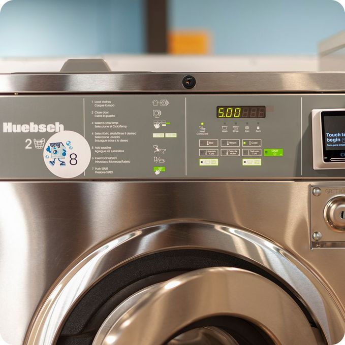 Close-up of a stainless steel Huebsch commercial washing machine. Best Laundromat in Memphis, TN.