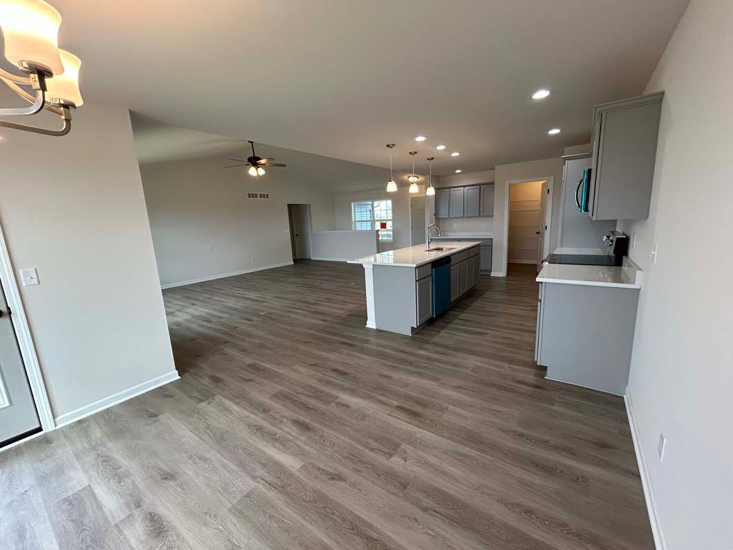 Open-concept kitchen and living area with gray cabinetry, island, and wood-look flooring.