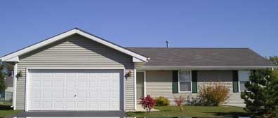 A beige ranch-style house with a white garage door, under a clear blue sky.