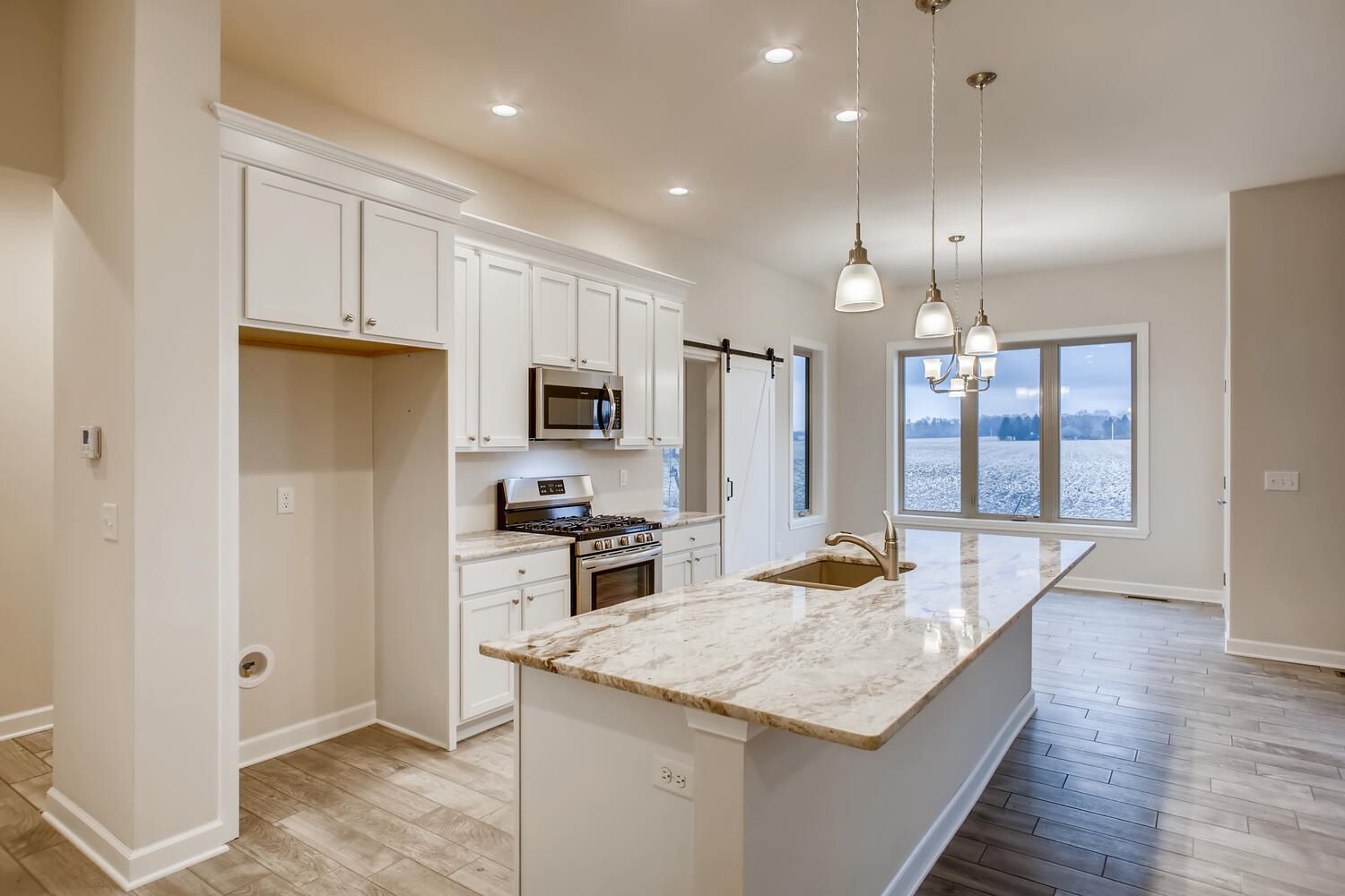 Bright kitchen with white cabinets, granite island, and a sliding door.