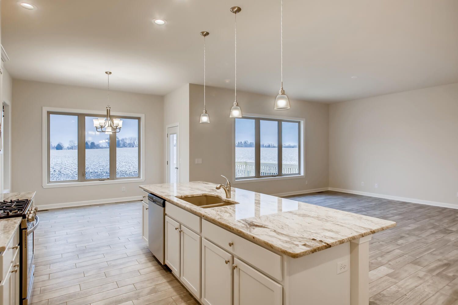 Bright kitchen with island, windows, and pendant lights. White cabinets, granite counters, and stainless steel appliances.