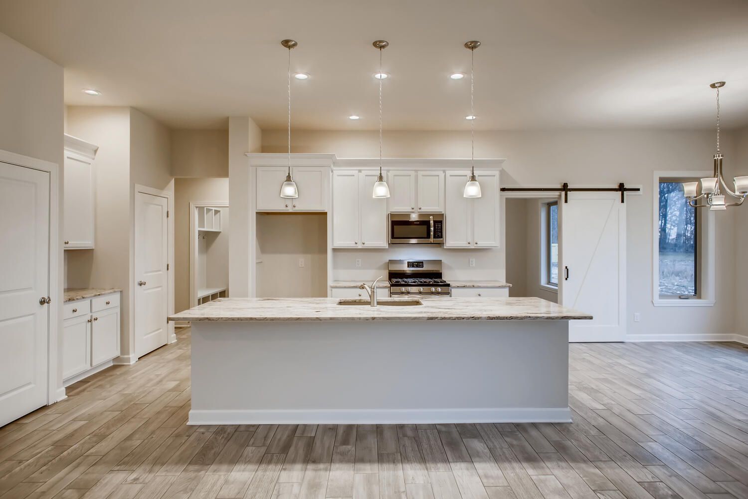 Bright, white kitchen with an island, stainless steel appliances, and hardwood floors.