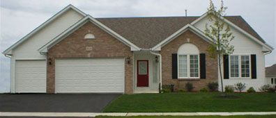 A single-story house with a brick facade, white siding, and a red front door, with a green lawn and asphalt driveway.