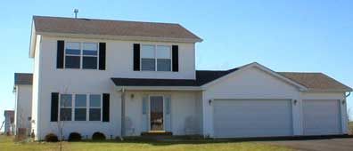 White two-story house with black shutters, a garage, and a blue sky.