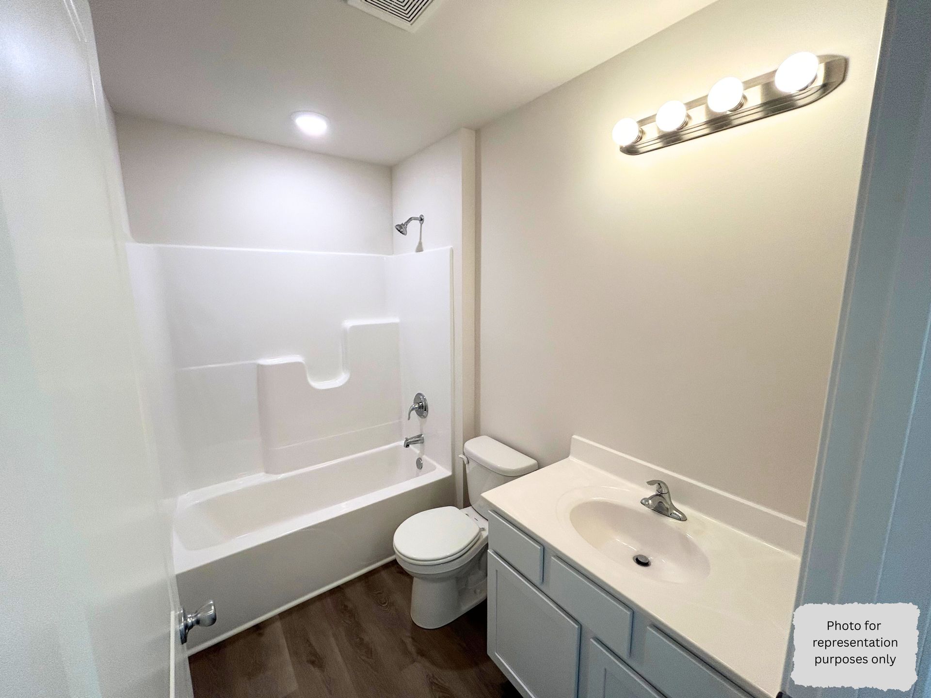 Bathroom with white fixtures, gray walls, and dark wood-look flooring.