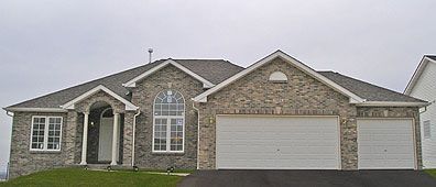 Brick house with white trim, two-car garage, and overcast sky.